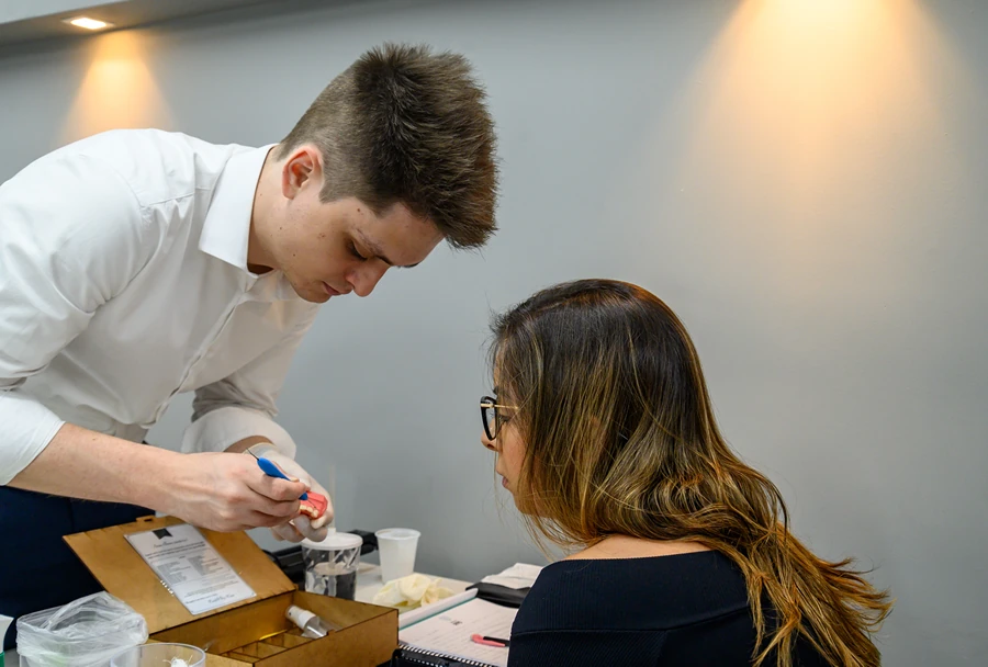Instrutor orienta participantes que manipulam materiais odontológicos em um workshop do Instituto IPPO.