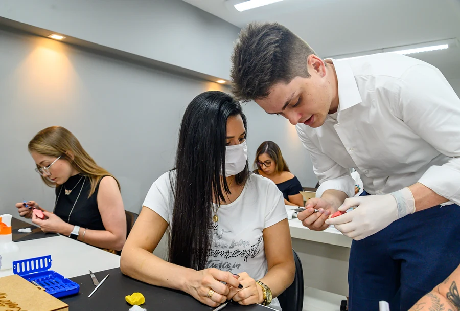 Instrutor demonstra técnica odontológica para participante que observa atentamente no Instituto IPPO.