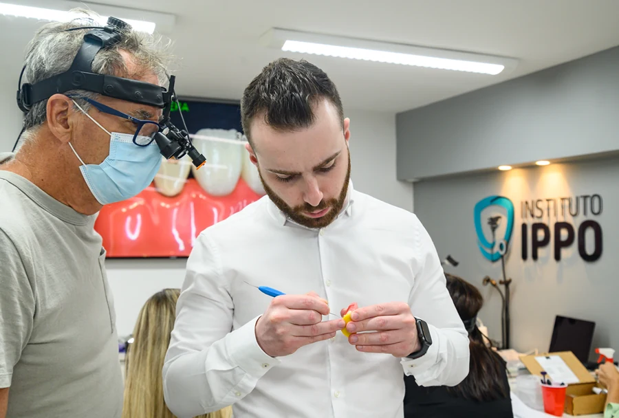 Instrutor e participante com lupa odontológica colaboram durante prática em curso do Instituto IPPO.